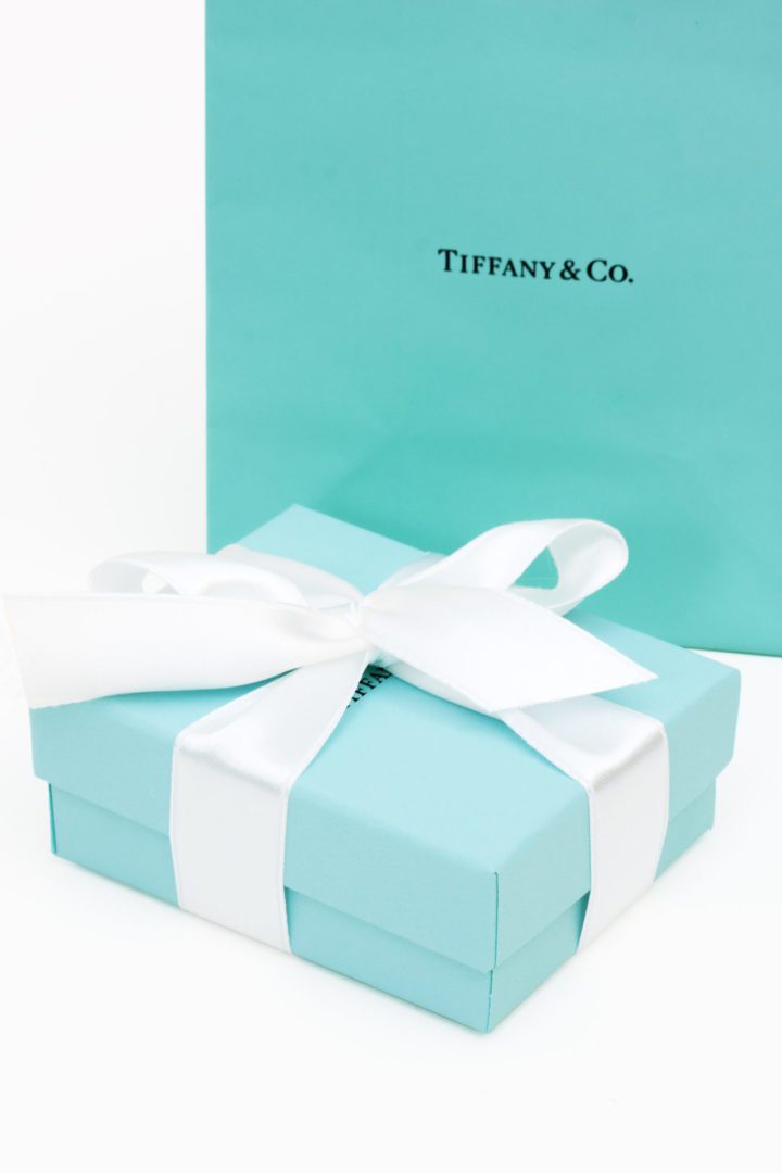 The iconic Tiffany and Co. blue gift box with white ribbon on white background..
